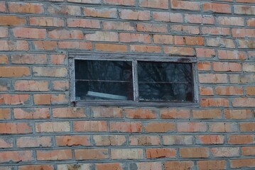 one small rectangular old window on a brown bricks wall of a house on the street