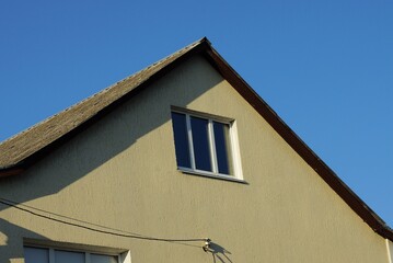 Fototapeta na wymiar brown loft of a private house with one window outside against a blue sky