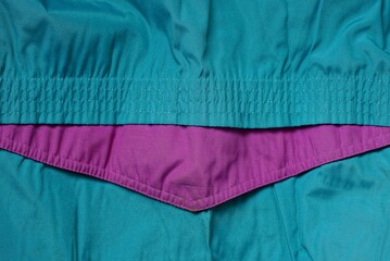 colored texture of crumpled green fabric with a seam and a lilac stripe on clothes