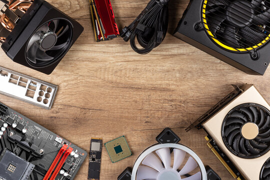 modern desktop computer hardware components on wood desk table background. Circle shaped of pc parts like cpu fan cooler motherboard ram graphics card ssd and power supply wood technology concept.