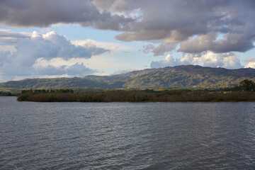 Lake dam landscape with reflection of Gardunha mountains and trees on a cloudy day in Santa Agueda Marateca Dam in Portugal