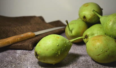 Green pear close up, with drops of water, more units on the stone background.