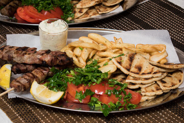 .Fried souvlaki with greek salad, potatoes and tzatziki sauce in plate