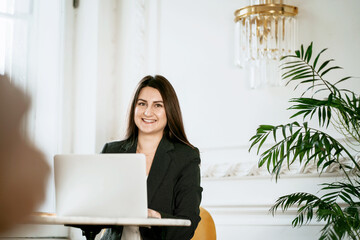 The student studies the basics of economics. College education. The psychologist is a brunette of Caucasian appearance. Sitting in a comfortable chair and reading an electronic textbook on a laptop. 