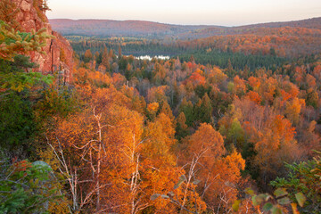 Hills trees and a small lake surrounded by trees in autumn color at sunrise in northern Minnesota