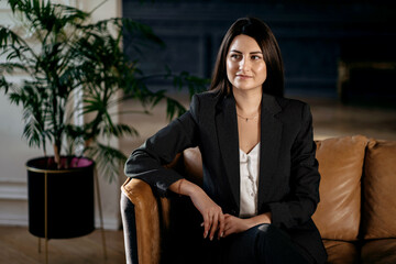 The psychologist is a female student in a business suit of European appearance. The manager is sitting on the couch. Modern and stylish office. Illuminated by sunlight. 