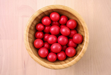 Delicious candies, nuts in red glaze lie in a bowl made of bamboo.