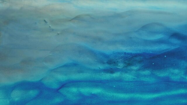 Ink water motion. Underwater stream. Sea wave animation. Blue glitter mist flow revealing beige grain sand dynamic surface abstract art background.