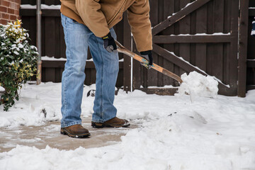 Closeup of person with shovel clearing snow from sidewalk