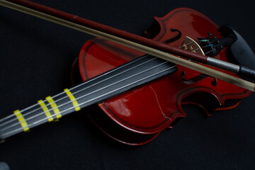 Close view of a classical small violin, strings and bridge over a dark black blanket background
