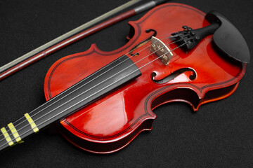 Fototapeta na wymiar Close view of a classical small violin, strings and bridge over a dark black blanket background 