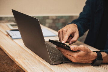 Close up man using smartphone and laptop computer on table