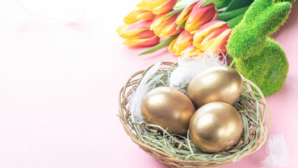 Egg color. Happy Easter decoration: golden colour eggs in basket with spring tulips, white feathers on pastel pink background. Foil minimalist egg design, modern template.