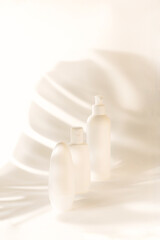 White bottles mockup for branding. Set of cosmetic products for cream, soup, deodorant, shampoo with shadows of monstera. Tubes, dispensers and jars