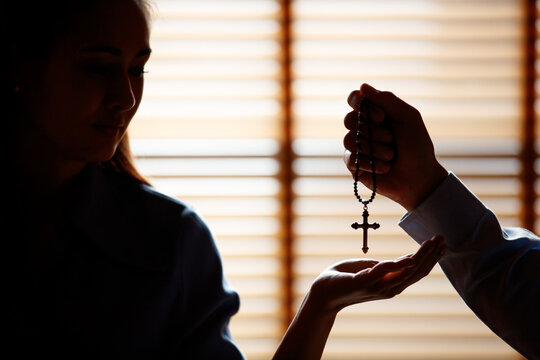 Image is Silhouette. Asian man is giving a cross to a Christian woman with a smiling face. To pray to Jesus Confession to God. Concept faith prayer love giving..