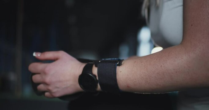 Close-up female cross fit athlete with smart watch puts protective wrist straps on hands preparing to exercise at gym.