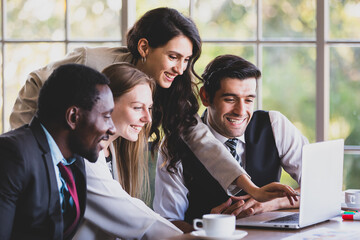 Professional middle-aged caucasian businesswoman manager consulting planning strategy to concentrated multiracial colleagues that gathered in front of a laptop while sitting at office working table