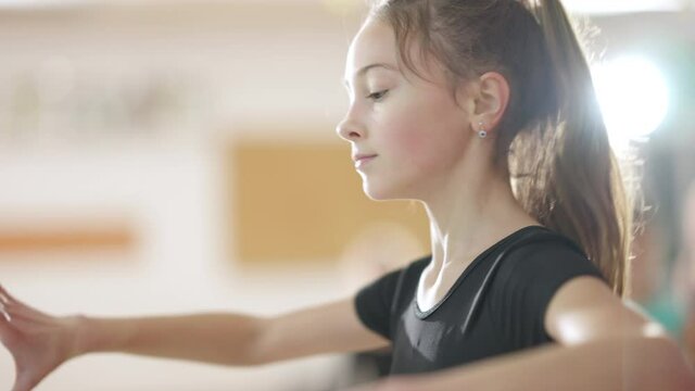 Concentrated girl rehearsing ballet dance with help of teacher in dance studio. Focused skilled Caucasian children studying classical dancing indoors. Professional teaching kids. Art and skill concept