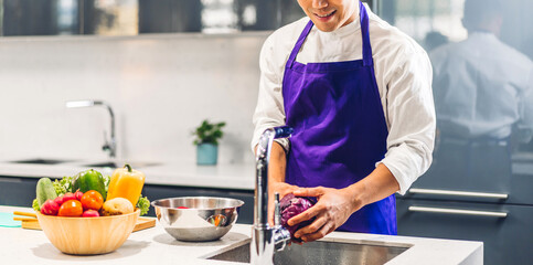 Portrait of smiling professional handsome asian man chef cooking and preparing salad with cooked food on counter standing in the restaurant commercial kitchen
