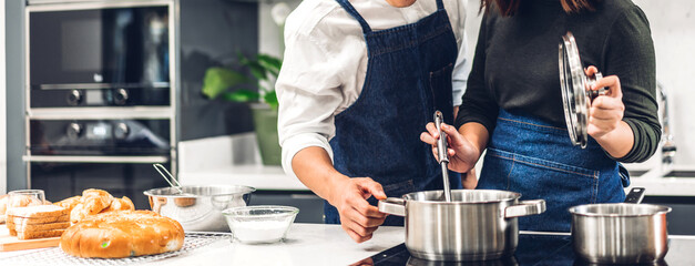 Young asian family couple having fun standing near stove and cooking together.Happy couple looking...