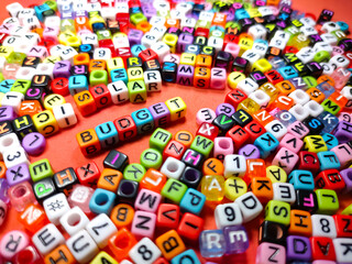 Selective focus.Colorful dice with word BUDGET on red background.Shot were noise and film grain.