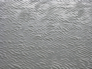 Ripples made by sand and water in an abstract pattern on sea bed over sand
