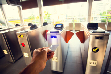Selective focus to hand of passenger using smart card to open automatic gate machine at sky train...