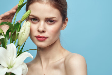Beautiful girl with a bouquet of white flowers on a blue background cropped view naked shoulders portrait