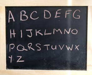 Obraz premium alphabet written on black chalkboard with pink chalk.