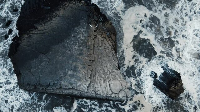 Vista a&eacute;rea con drone de las olas golpeando las rocas de las costas del mar, olas bailando en el duro casco de las rocas