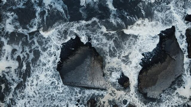 Vista a&eacute;rea con drone de las olas golpeando las rocas de las costas del mar, olas bailando en el duro casco de las rocas