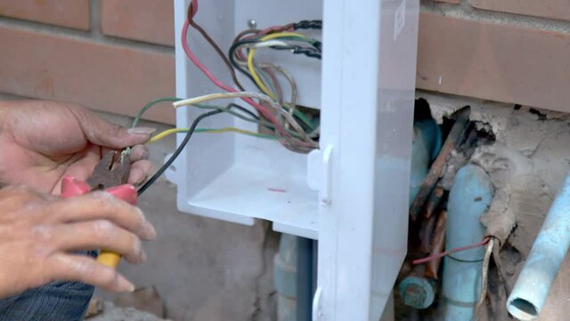 Hand Close Up – Asian Air conditioning technician making inadequate electrical wiring for air conditioning installation. Inadequate electrical wiring concept. 
