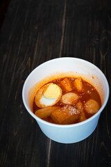 Stir-fried Rice Cake Tteok-bokki in a takeaway container. Korean food delivery.