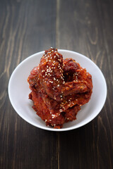 Chunks of fried chicken in a spicy sauce and sesame seeds. Food Korean cuisine on a wooden background.