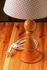 Side view of a wooden table lamp on a pine table top close-up