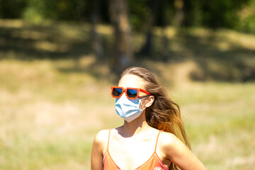 Girl with red pixel sunglasses wearing a prectection mask on a sunny day in pandemic times. High quality photo