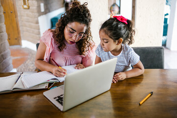 latin mother works on laptop with children playing around, Work from home. 