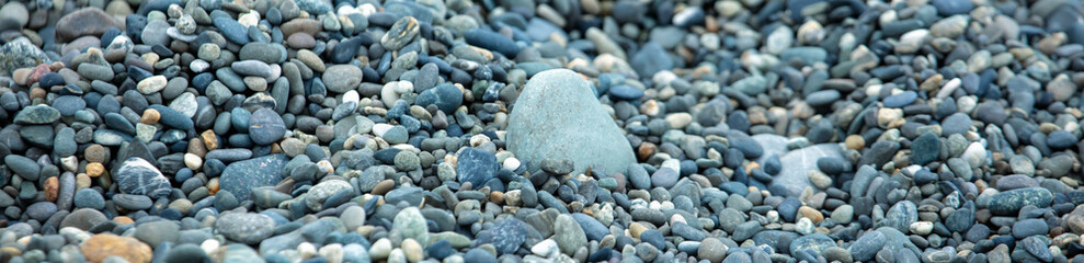 Fototapeta na wymiar Stone pebbles on the seashore as a background. Close-up
