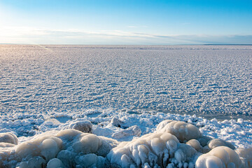 View of the frozen sea, stones in the foreground. clear sky