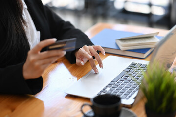 Cropped shot of female holding credit card shopping online or making online payment with laptop.