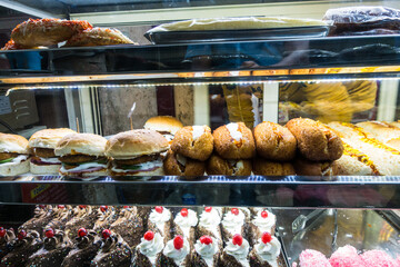 Baked cakes and snack food on display in glass cabinet
