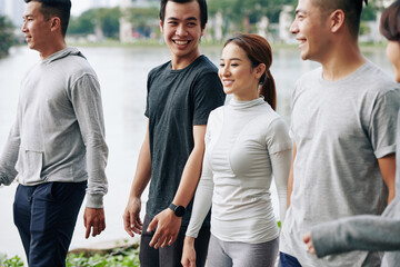 Happy fit young Asian people walking outdoors after training together in park