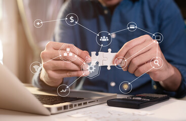Business partnership concept. Businessman hand connecting jigsaw puzzle with calculator at office in morning light.