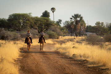 Two horsewomen ride along dirt track side-by-side
