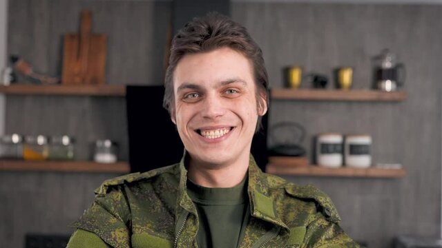 Portrait of a young soldier in army clothes. The man is happy to return home.