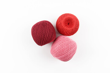 Crimson, red and pink balls of cotton crochet thread on a white background. The concept of a favorite hobby of handwork, needlework and needlework. Top view. Flatlay. Copyspace.