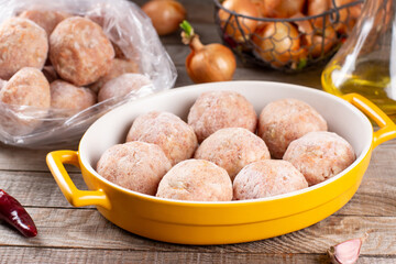 Frozen meatballs in a baking dish on a wooden table