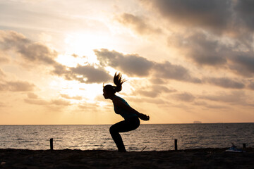 Silhouette woman jumping on the beach has to background the sunrise. Run towards the goal for new year concept