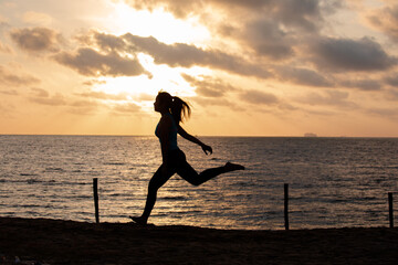 Silhouette woman running on the beach has to background the sunrise. Run towards the goal for new year concept