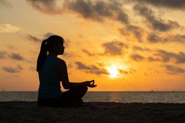 Silhouette Calm relaxed woman meditating and smile on the beach have to background the sunrise. New life for new year concept
